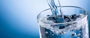 Pouring water into glass on blue background